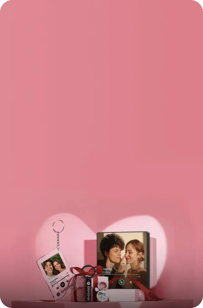 Personalized music player display with photo keychain, red gift box, and portrait of smiling couple against pink background with heart shape light.